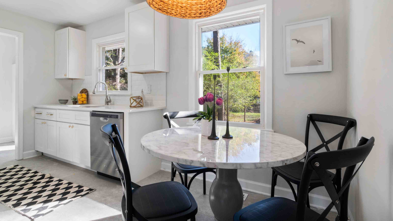 a-white-round-engineered-marble-dining-table-with-black-chairs-in-a-kitchen